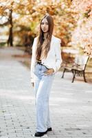 Vertical photo. Beautiful carefree young teenage girl in casual clothes. Portrait of a beautiful girl against the background of nature with a blurred background. photo