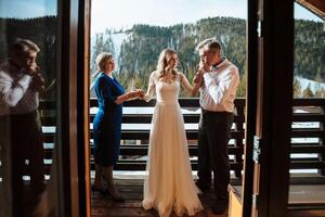 contento padres ayuda y alegrarse para su pronto a casarse hija. conmovedor momentos a el boda. mamá suavemente sostiene su hija mano, papá suavemente Besos el de la novia mano foto