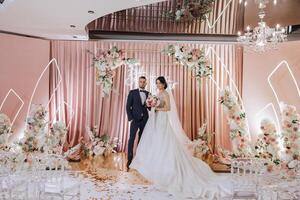 Wedding. Love and couple. Celebrating the ceremony and commitment. Save the date. Trust. The bride and groom embrace. Photo of a happy and bride and groom against the background of a ceremonial arch.