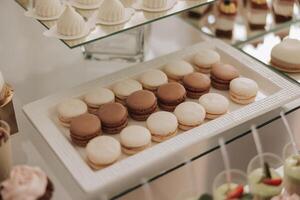 macarrones de cerca de un caramelo bar a un Boda banquete. un delicioso recepción, un lujoso ceremonia. mesa con dulces y postres delicioso vistoso francés postres en un plato o mesa. foto