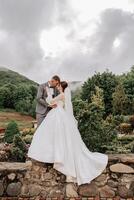 Wedding. Love and couple in garden for wedding. Celebration of ceremony and commitment. Save the date. Trust. The groom embraces the bride against the background of mountains and a cloudy sky. photo