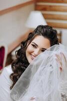 A beautiful brunette bride with a tiara in her hair is getting ready for the wedding in a beautiful robe in boudoir style. Close-up wedding portrait, photo. photo