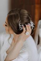 Luxurious wedding barrette on the head of the bride's hairstyle. The morning of the wedding preparation of the bride who touches the hairpin on her head with her hand. photo