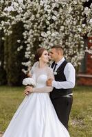 Wedding. Love and couple in garden for wedding. Celebration of ceremony and commitment. Save the date. Trust. The bride and groom embrace. The groom embraces the bride under a spring flowering tree. photo