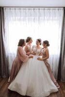 Friends rejoice with the bride in the morning. They take pictures, smile, help the bride fasten her dress. photo