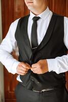 the man fastens the buttons on his jacket. The groom is preparing for the wedding ceremony. Detailed close-up photo of hands