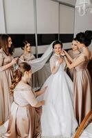 The bridesmaids help the bride get dressed. Preparation for the wedding. Morning of the bride photo