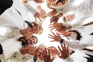 A large group of smiling young people standing, hugging, looking at the camera and stretching their arms down. Group of cheerful teenage people in a circle looking down. Low viewing angle. Copy space. photo