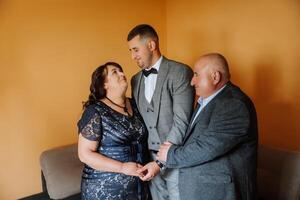 photo with parents at the wedding. Happy parents rejoice for their son who will soon get married. Touching moments at the wedding