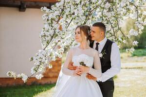 Wedding. Love and couple in garden for wedding. Celebration of ceremony and commitment. Save the date. Trust. The bride and groom embrace. The groom embraces the bride under a spring flowering tree. photo