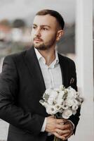 portrait of a handsome man with flowers in his hands on the balcony of a hotel room in the morning. Preparation for an event or a new working day. New opportunities, acquaintances. Close-up portrait photo