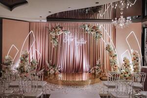 un hermosamente decorado sitio para el Boda ceremonia de el novia y novio en un moderno estilo. Boda arco hecho de blanco y rosado Fresco flores hermosa decorativo sillas y dorado piernas foto