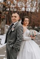 The groom comes up behind the bride and embraces her. Sincere emotions. A walk in the forest. Winter wedding photo
