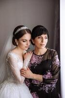 A beautiful and happy mother and her daughter, the bride, are standing next to each other. The best day for parents. Tender moments at the wedding. photo