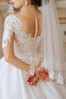 Lace and embroidery on fabric with beads wedding dresses on the mannequin. Skillful female dressmaking adjusting buttons on clothing. Amazing wedding dress on a mannequin. photo