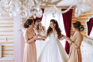 Friends rejoice with the bride in the morning. They take pictures, smile, help the bride fasten her dress. photo