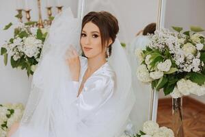 A beautiful brunette bride with a tiara in her hair is getting ready for the wedding in a beautiful robe in boudoir style. Close-up wedding portrait, photo. photo