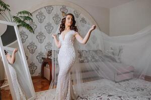 A wonderful beautiful portrait of a young bride. Beautiful bride with wedding makeup and jewelry wreath on long curly hair. Wedding photo model with brown eyes in a beautiful interior.