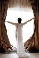 Rear view of woman standing near window of modern luxury apartment or hotel room. photo