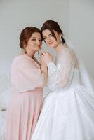 A beautiful and happy mother and her daughter, the bride, are standing next to each other. The best day for parents. Tender moments at the wedding. photo