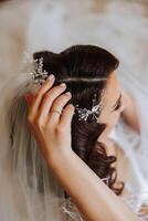 Luxury. Rich Stylish Brunette with Pearly Beads. Elegant Style. Close-up shot of female hair-do made as a strand of hair fixed with a gold hair clip. photo