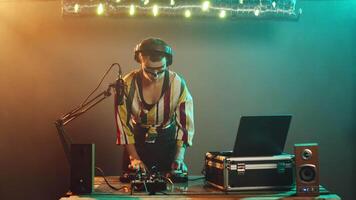 Cool disc jockey doing mute sign to haters, being focused on mixing techno music at nightclub performance. Woman artist with crazy makeup showing hush symbol to keep silence. Tripod shot. video