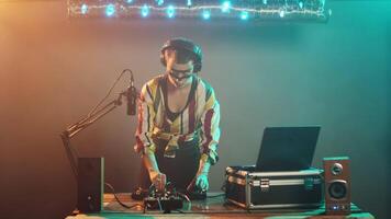 Cool musician presenting stop sign with palm raised, mixing modern sounds using headphones at turntables. Female DJ artist creating rejection and denial symbol at club. Tripod shot. video