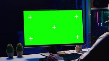 Man chatting with friends online while playing together in multiplayer game on isolated screen desktop PC, close up. Player cooperating with teammates in coop videogame using chroma key monitor video