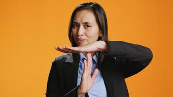 Young woman showing timeout symbol in studio, asking for a break after working hard. Asian person standing over background, presenting pause gesture with hands, confident model. video