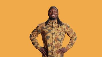 Athletic person flexing his arms muscles in studio and pointing up, showing off his strength and biceps standing over orange background. African american guy indicating upwards direction. video