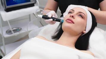 profissional dermatologista dentro médico luvas fazendo facial hidro descamação procedimento para lindo mulher paciente dentro cosmetologia clínica. fechar acima vácuo facial tratamento. video