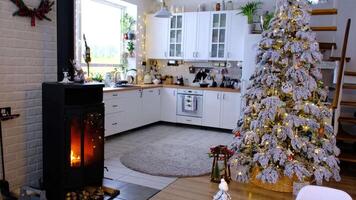 Noël décor dans blanc cuisine avec brûlant le fourneau cheminée, de fête désordre, village intérieur avec une neigeux Noël arbre. Nouveau année, Noël humeur, confortable maison. video