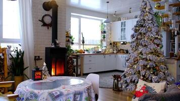 Christmas decor in white kitchen with burning stove fireplace, festive mess, village interior with a snowy Christmas tree. New Year, Christmas mood, cozy home. video