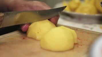 mani di un anziano donna taglio patate su un' taglio tavola. video