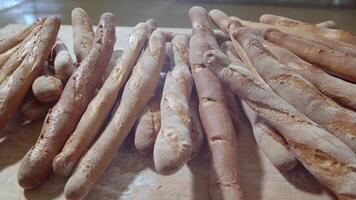 fresco al forno lungo baguette pane menzogna su il di legno tavolo cosparso con Farina nel un' mucchio video