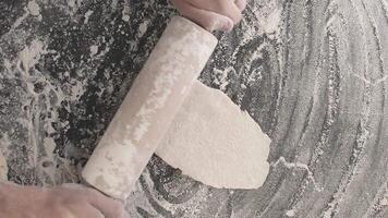 Male hands roll out baking dough using rolling pin on a wooden board video