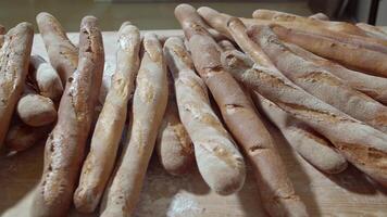 vers gebakken lang baguette brood liggen Aan de houten tafel besprenkeld met meel in een stapel video