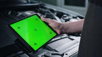 Worker, auto mechanic touching chroma key computer pad while doing engine diagnostics. Unrecognizable person using mockup tablet. video