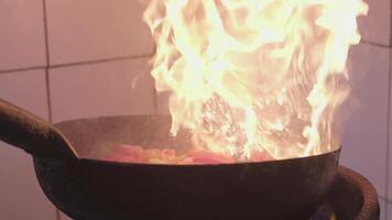 Fresh veggies are flambeing on a frying pan over open fire video