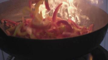 Fresh veggies are flambeing on a frying pan over open fire video