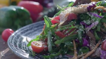 avvicinamento di fresco insalata fatto di rosso cavolo, pomodori, cipolle, basilico, rucola e pezzi di fritte carne video