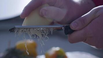 Close-up of hard cheese is grated on a small grater holding in hands video