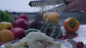 Close-up of hard cheese is grated on a small grater holding in hands video