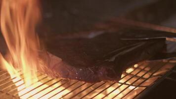 Close-up of big stake grilled on the big open fire and turned with tongs video