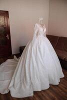 Bedroom interior with wedding dress prepared for the ceremony. A beautiful lush wedding dress on a mannequin in a hotel room. photo