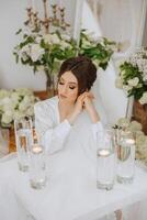 A beautiful brunette bride with a tiara in her hair is getting ready for the wedding in a beautiful robe in boudoir style. Close-up wedding portrait, photo. photo