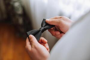 man's tie in hands, close-up photo of hands. The groom is preparing for the ceremony. Last preparations.