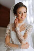 Moda retrato de un hermosa novia en un lujoso Boda vestir con cordón y cristales en un Arábica interior estilo. hermosa novia con un ramo de flores de flores preparación para el Boda ceremonia. foto