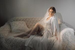 Nice cute girl in a boudoir robe. Happy beautiful bride under veil. Fashion, beauty, style. Morning of the bride. Beautiful bride with stylish make up and hair style. photo