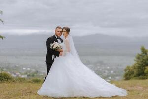 The bride and groom stand face to face with green hills in the background. A beautiful photo session of the bride and groom in the mountains. Free space.